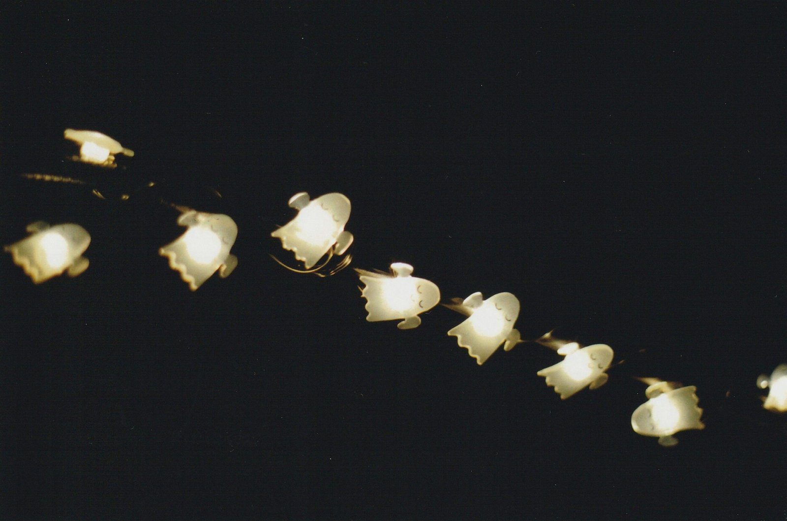 String lights featuring ghost shapes illuminate a dark background, perfect for Halloween decor.